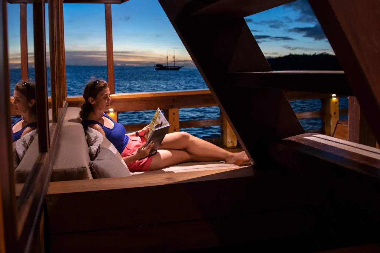 Guests reading on the shaded upper deck of a liveaboard