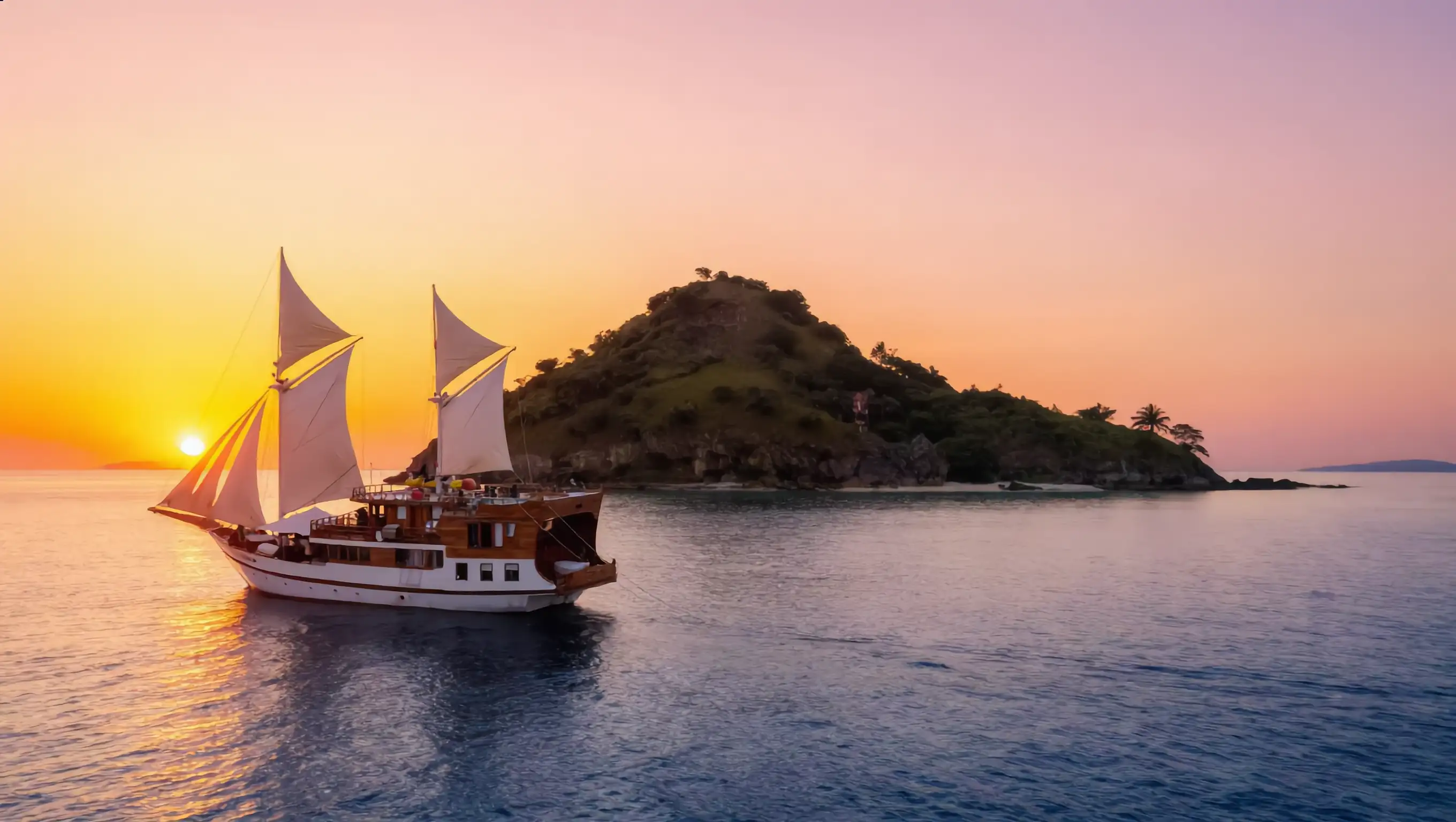 A phinisi under sail at sunset on the crossing toward Flores